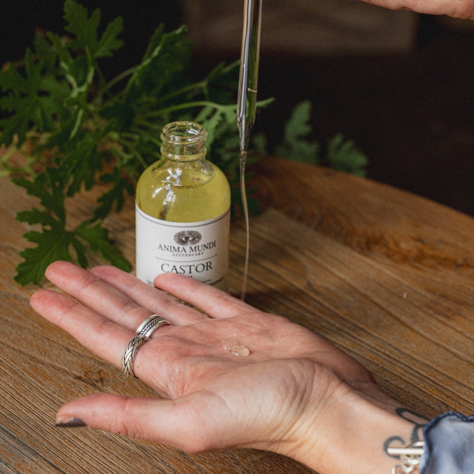 Application d'huile de Ricin de Anima Mundi sur la paume d'une main. Soin hydratant et fortifiant pour peau, ongles et cuir chevelu. Huile végétale naturelle.