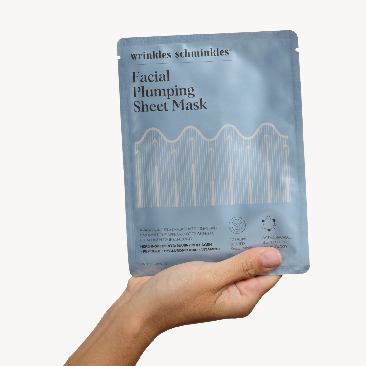 Main tenant un sachet du Masque en Tissu Repulpant Pour Le Visage de Wrinkles Schminkles. Eclat immédiat "glass skin".