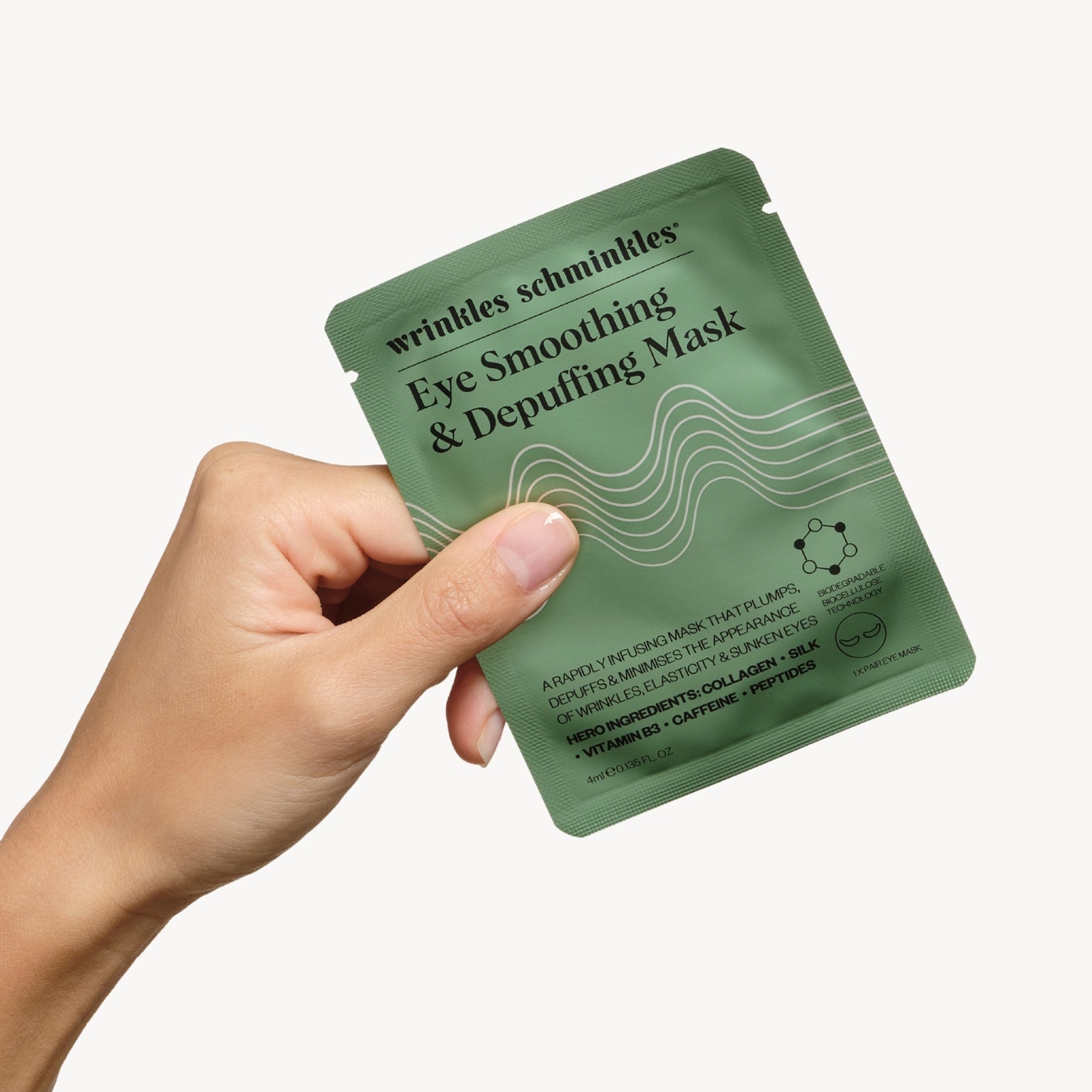 Main tenant Masque Lissant Et Décongestionnant Pour Les Yeux de Wrinkles Schminkles. Masque en tissu biodégradable.