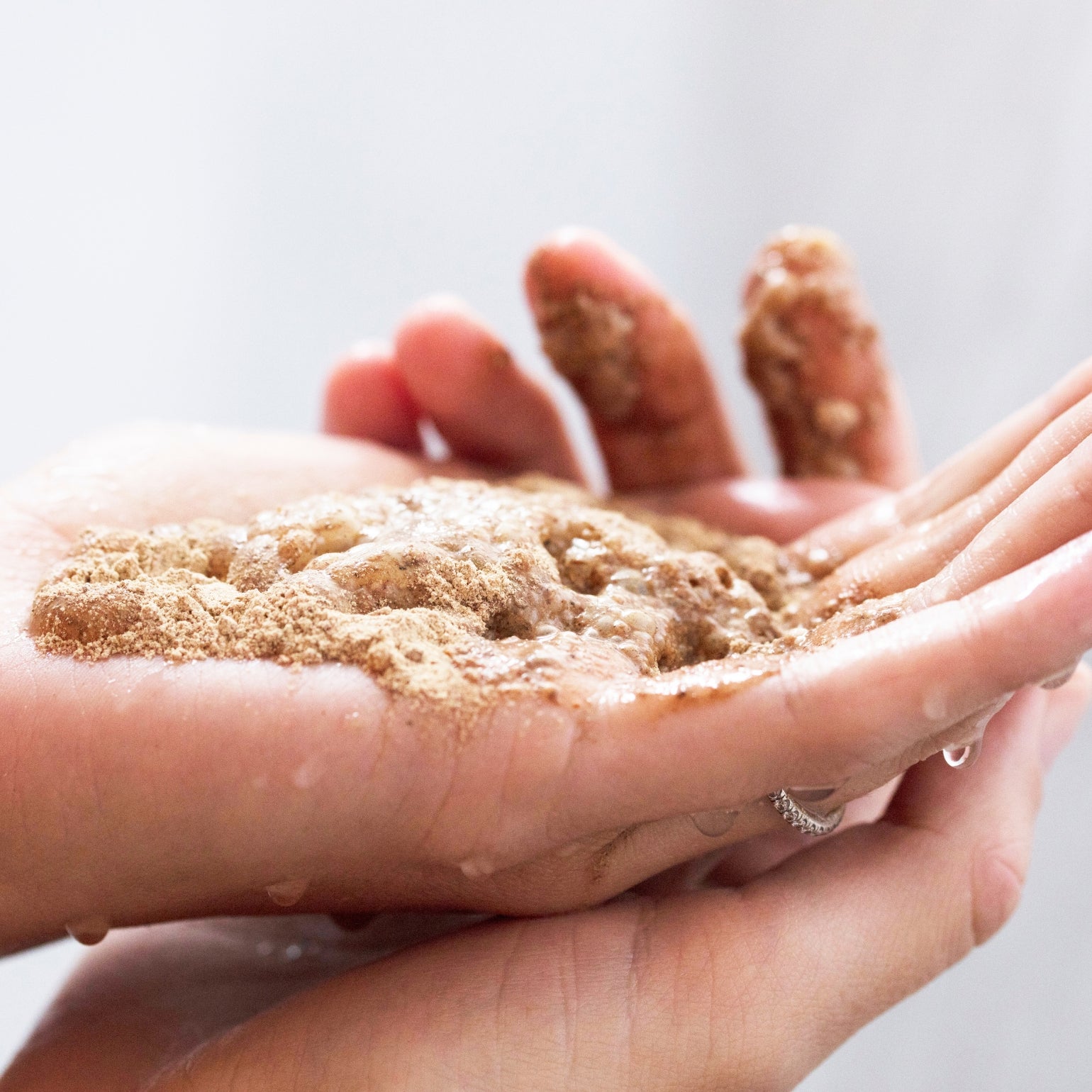 Main tenant The Clean Dirt de May Lindstrom. Le produit mousse au contact de l'eau. 